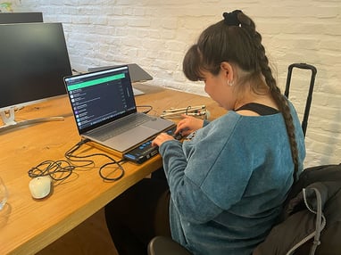 Carina testet die Quiply Mitarbeiter-App am Laptop und liest Inhalte über eine Braillezeile.